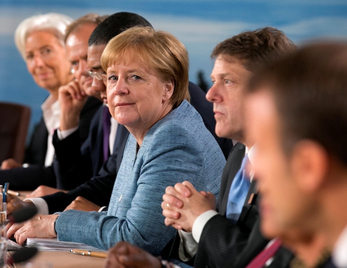 Angela Merkel est assise à une table avec d'autres personnes.