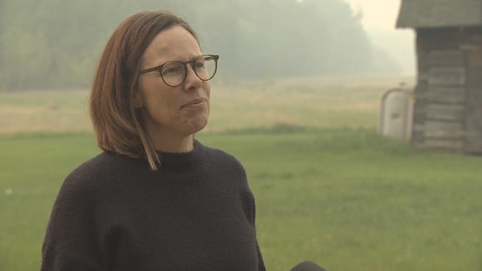 Une femme regarde en face avec, en arrière-plan, un paysage brumeux.