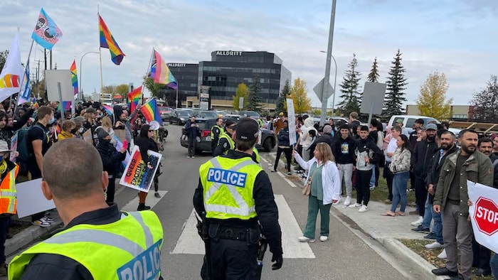 Des manifestants occupent la rue à Edmonton, sous surveillance policière, certains brandissant des drapeaux de la fierté, à Edmonton, 2023.