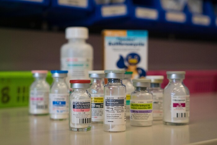 On voit en gros plan plusieurs flacons d'antibiotiques sur un comptoir de la pharmacie d'un hôpital.