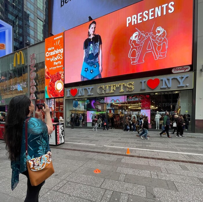 Une personne prend un cliché d'un panneau publicitaire à New York sur lequel figurent des créations de mode inuit.