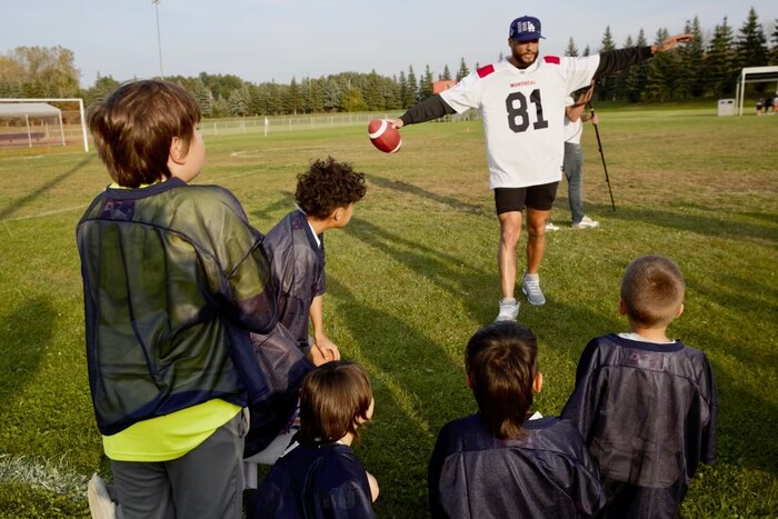 This groups of children from Kahnawà:ke learn the ins and outs of football from Alouettes wide receiver Austin Mack. (Ka’nhehsí:io Deer/CBC)