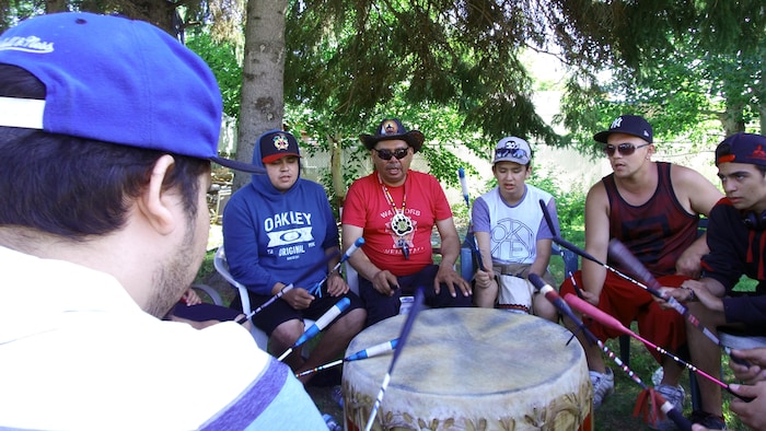 Jocelyn Bellemare et Noah Petiquay, un jeune placé chez lui depuis sept ans, répètent avec le groupe lors du Pow-wow de Mashteuiatsh en 2017