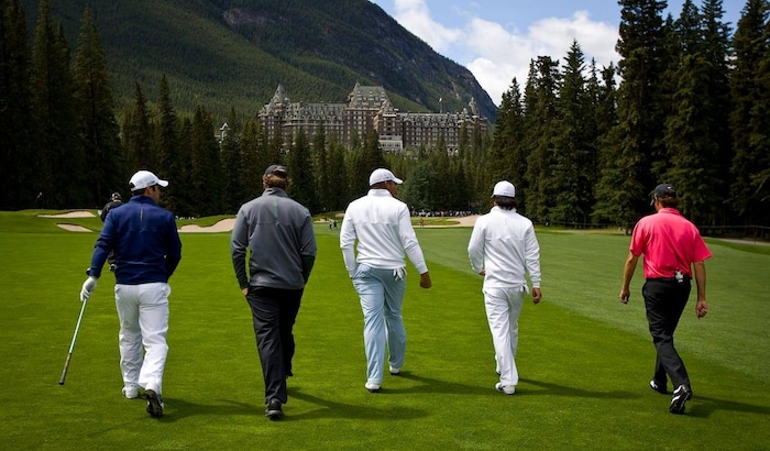 Golfers walk along a fairway towards the Banff Springs Hotel in Banff, Alta.