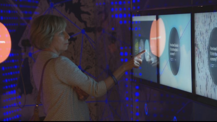 Une visiteuse consulte un écran interactif dans une salle du Musée de la Banque du Canada. 