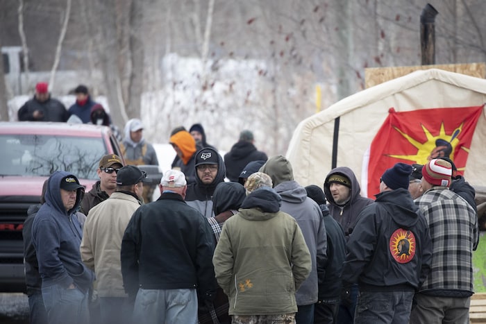 Une quinzaine de personnes sont rassemblées et discutent près de la barricade à Kahnawake.
