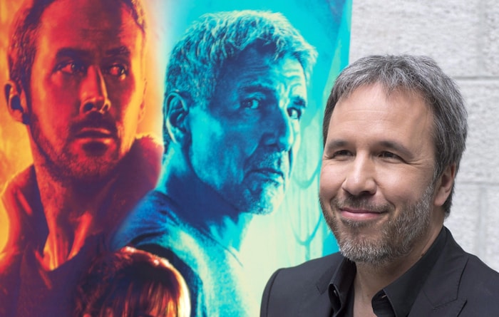 Denis Villeneuve sourit devant l'affiche du film « Blade Runner 2049 »