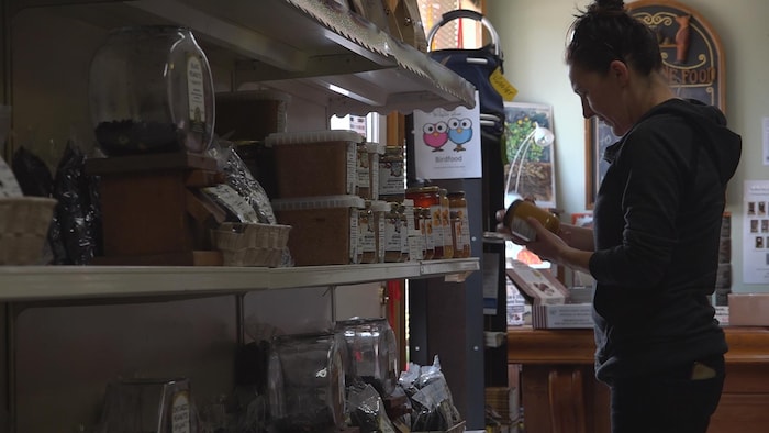On voit une femme en train de lire l'étiquette d'un produit à base d'arachides dans la boutique de Kernal Peanuts.