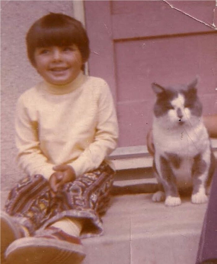 An old photograph of a child sitting next to a cat.
