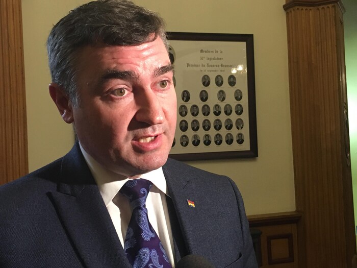 Le député MacDonald s'adresse aux journalistes dans le hall de l'Assemblée législative.