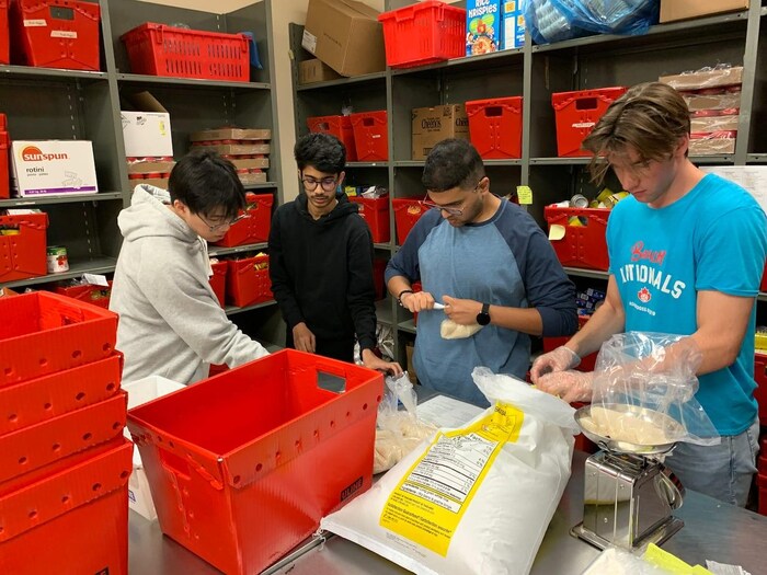 Four young people dividing rice into small portions in a food bank.