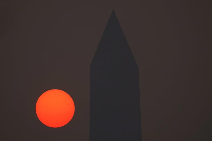The sun rises behind the Washington Monument and a thick layer of smoke, Thursday, June 8, 2023.