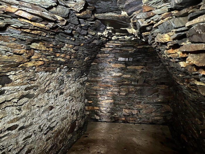 Une chambre souterraine en pierre avec un plafond en voûte.