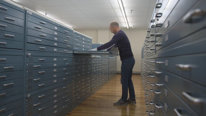 Un homme place un document dans un vaste classeur.