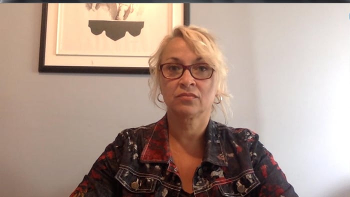 Une dame blonde avec des lunettes face à sa webcam