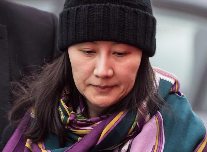 La directrice financière de Huawei, Meng Wanzhou, portant tuque et châle en compagnie d'un agent de sécurité à Vancouver, le 12 décembre 2018.