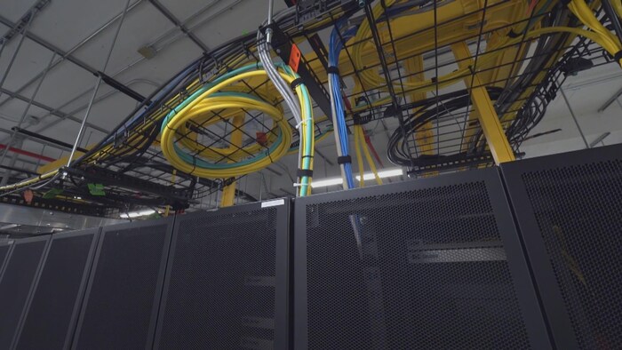 On voit de nombreux câbles enroulés et attachés au-dessus des serveurs.