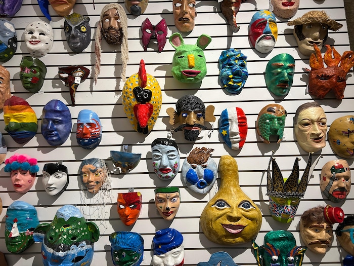 Des dizaines de masques de tous les styles sont suspendus à un mur.