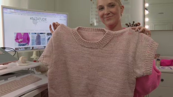 Une femme tient un tricot entre ses mains.