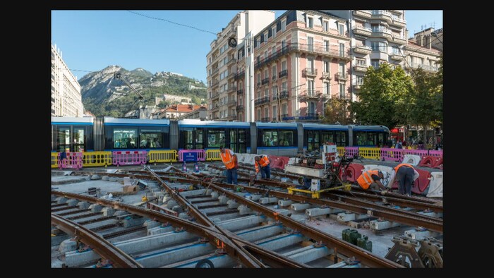Chantier d'implantation du tramway à Grenoble. Des travailleurs mettent en place des rails
