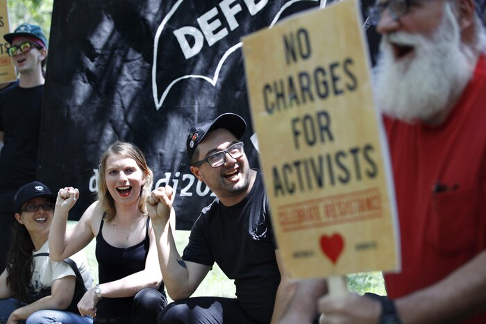 Chelsea Manning et Dylan Petrohilos sont souriants et ont le poing levé en guise de protestation. 