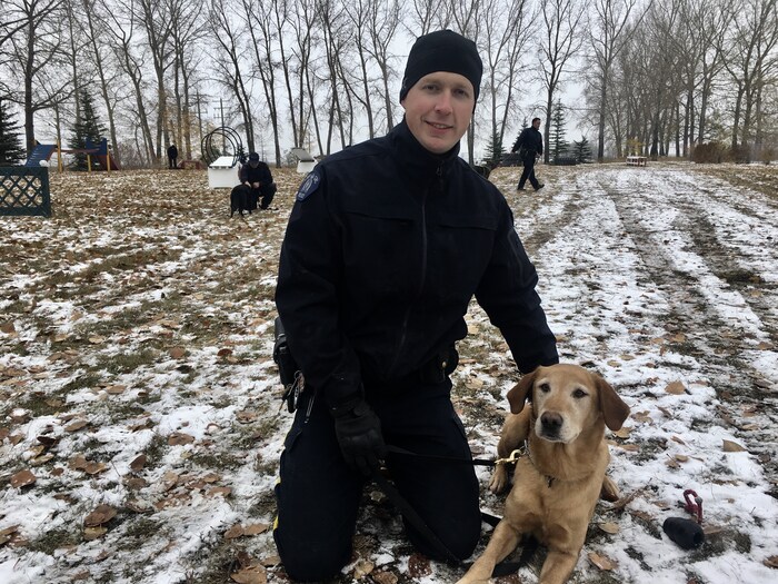 Le gendarme Jason Frederick est accroupi dans la neige avec son chien Henry, maintenant retraité. 