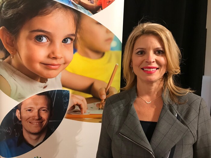 Femme souriante devant une affiche promotionnelle pour l’éducation.
