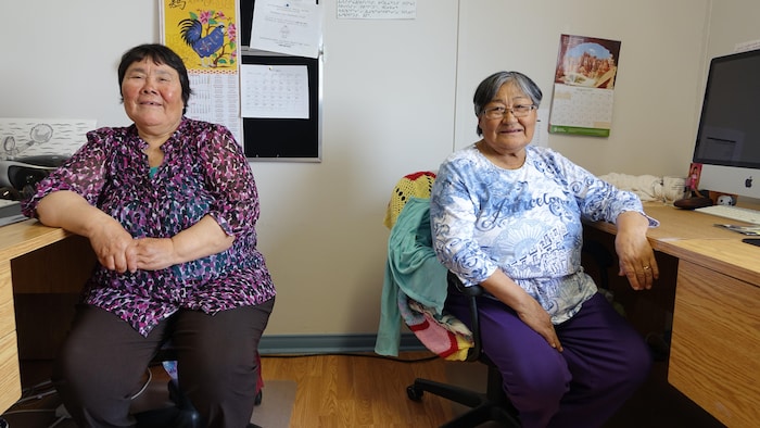 Deux femmes assez âgées assises à des bureaux.