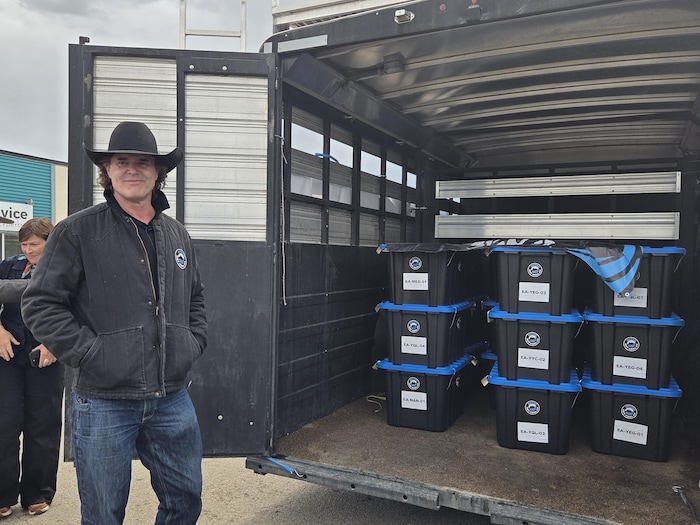 Le chanteur Corb Lund pose devant les boites de sa pétition contre l'exploitation du charbon en Alberta