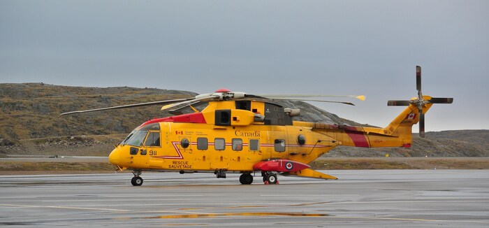 Un hélicoptère militaire Cormorant jaune posé au sol.