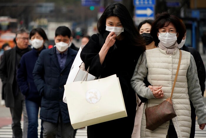 Des piétons portant des masques marchent dans les rues de Séoul.  