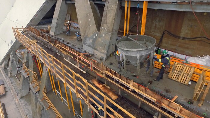On voit des ouvriers à l'oeuvre sur le bord d'un des étages de la tour du stade olympique en réfection. 