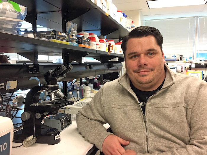 Craig Jenne pose dans un laboratoire rempli de matériel médical.