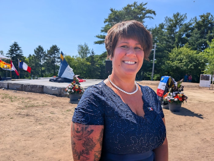 Une femme souriante pose pour la photo, devant un monument.