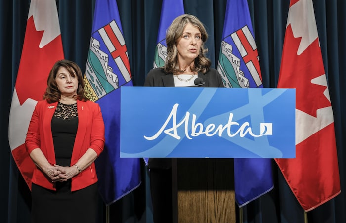 Deux personnes derrière un lutrin sur lequel on peut lire « Alberta ».