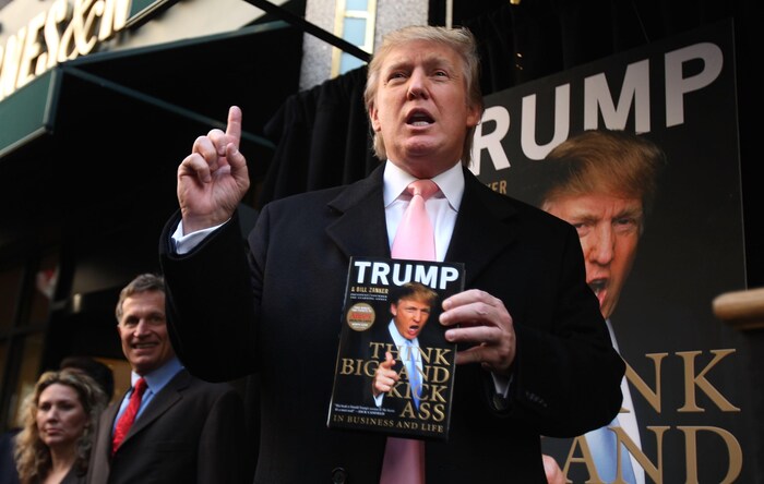 Donald Trump tient une copie de son livre. 