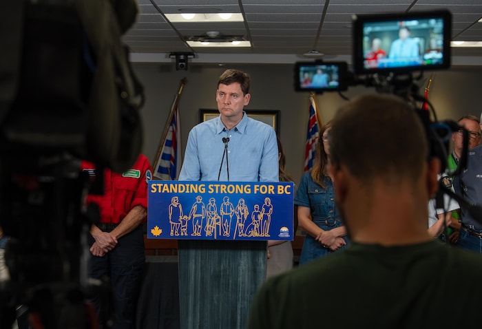 David Eby cadré à un podium entre deux caméras.