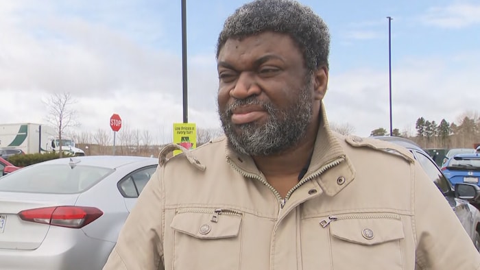 Un homme répond aux questions d'un journaliste dans un stationnement