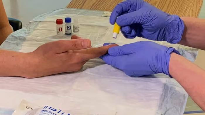 Un patient se fait prélever du sang à des fins de dépistage.