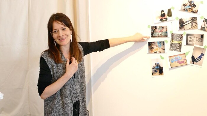 L'artiste Dominique Rey pointe au collage de photos sur le mur.