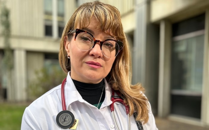 Une médecin vêtue d'une blouse blanche porte un stéthoscope au cou.