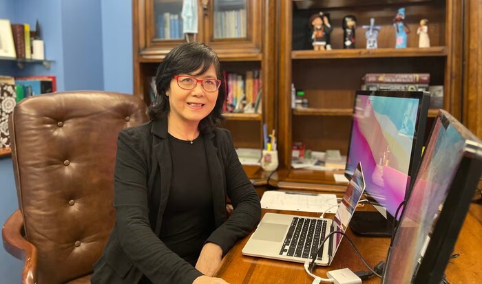 Une femme arborant un sourire devant un ordinateur dans un bureau.