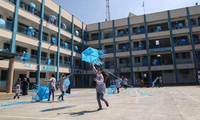 De jeunes filles s'amusent avec des articles promotionnels de l'UNRWA dans une cour d'école. 