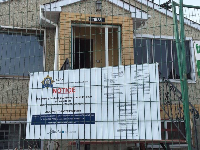 Une maison est derrière un grillage sur lequel une pancarte indique une ordonnance de fermeture de la propriété pour 90 jours.