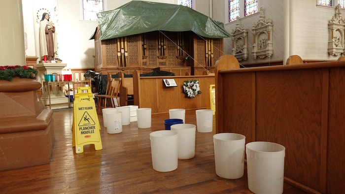 Des seaux en plastique disposés sur le plancher de l'église pour recueillir l'eau qui coule du toit.