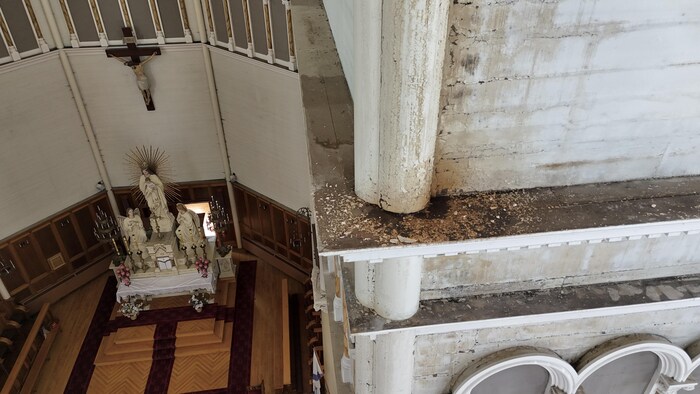 Une photo prise en hauteur montre des taches de moisissure et de la peinture écaillée sur des balcons au-dessus de l'autel d'une église catholique.