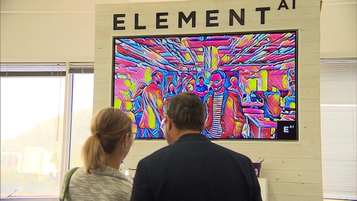 Deux personnes devant une affiche d'Element AI