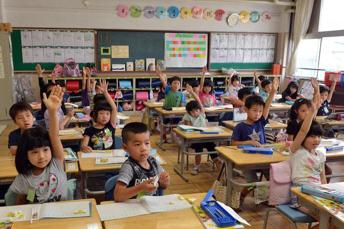 Des élèves lèvent la main dans une classe du primaire à Tokyo, au Japon