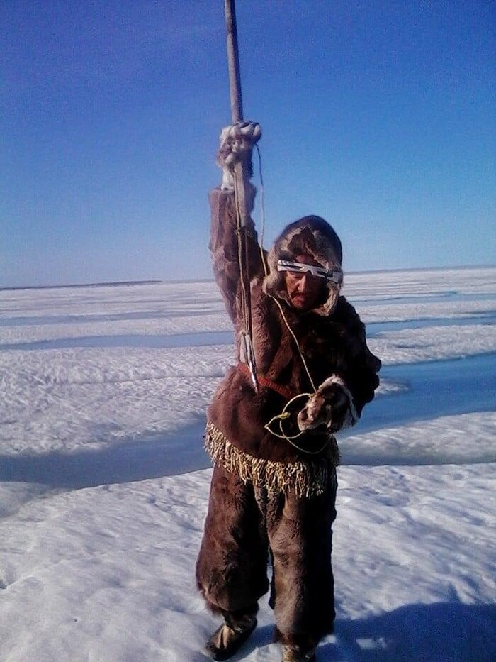 Eetak is on the ice, holding a harpoon, waiting for bearded seal in July 2020.