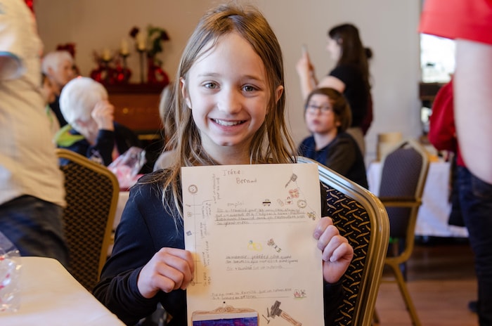 Une enfant qui tient une feuille.